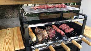 uma grelha com carne e salsicha em cima em Pousada Ondas de Floripa em Florianópolis