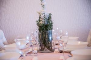 a table with glasses and a vase with flowers in it at Apartments Lulic in Crikvenica