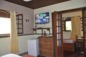 a bedroom with a tv on the wall and a dresser at Eco Pousada Eldorado Lumiar in Lumiar