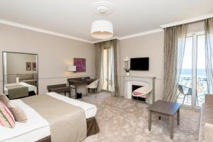 a hotel room with a bed and a living room at Hôtel Le Royal Promenade des Anglais in Nice