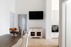 a white kitchen with a table and a tv on a wall at SC 2 Cozy Family & Business Flair welcomes you - Rockchair Apartments in Berlin