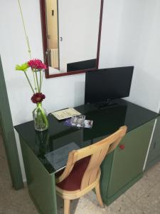 a green desk with a chair and a vase with flowers at Hotel Restaurante Logasasanti in Andújar