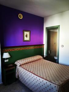 a bedroom with a bed with a purple wall at Hotel Restaurante Logasasanti in Andújar +15 photos