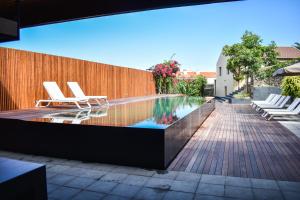 a swimming pool with chairs and a wooden fence at Volcanic Charming House in Ribeira Grande