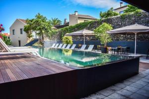 a swimming pool with chairs and umbrellas on a wooden deck at Volcanic Charming House in Ribeira Grande