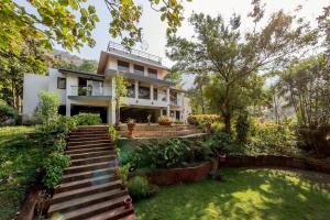 a house with a staircase in front of a yard at SaffronStays Masaya, Alibaug - pet-friendly villa with alfresco dining in Alibaug