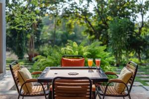 a table with chairs and two drinks on it at SaffronStays Masaya, Alibaug - pet-friendly villa with alfresco dining in Alibaug