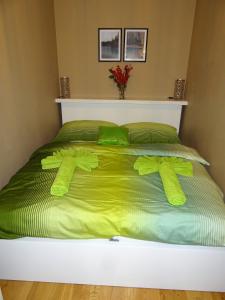 a bed with green comforter with two teddy bears on it at Medvědín Apartmán 106 in Špindlerův Mlýn