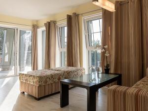 a living room with a table and a couch and windows at VacationClub - Rezydencja Bursztyn Apartament 31 in Świnoujście +12 photos