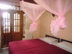 a bedroom with a bed with pink drapes at Jasmine Garden Inn in Ella