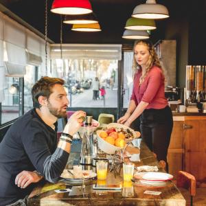 un hombre y una mujer sentados en una mesa comiendo comida en Hôtel Clarisse, en París