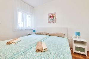 een witte slaapkamer met een groot bed met handdoeken erop bij Apartments Nina in Umag