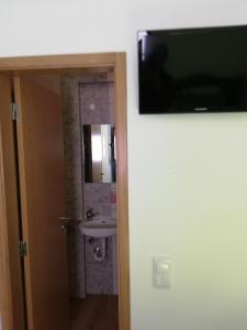 a bathroom with a sink and a television on a wall at Sol Mar in Odeceixe