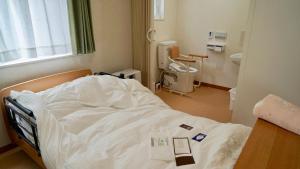 a hospital room with a bed and a bathroom at Taira no Yu in Kusatsu