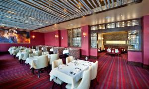 a dining room with white tables and chairs and pink walls at Northern Hotel in Billings