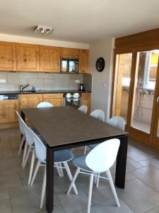 a kitchen with a black table and white chairs at Appartement Haute Nendaz met fantastisch uitzicht in Nendaz