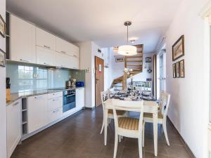 a kitchen with white cabinets and a table and chairs at VacationClub - Rezydencja Bursztyn Apartament 36 in Świnoujście