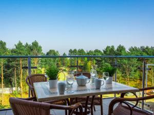 a table on a balcony with a view of trees at VacationClub - Rezydencja Bursztyn Apartament 36 in Świnoujście