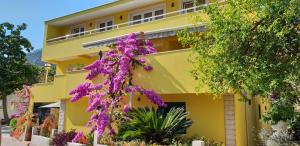 a yellow building with purple flowers in front of it at Apartments Marijan in Orebić