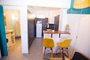 a small kitchen with yellow chairs and a table at Ti Barachois in Saint-Denis