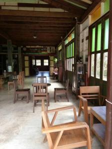 a room with wooden tables and chairs and windows at Khaokor Remind by Palek in Khao Kho