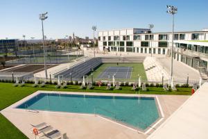 an empty pool with a tennis court in front of a building at Rafa Nadal Residence in Manacor
