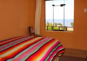 a bedroom with a colorful bed and a window at Inca lodge - Amantani in Ocosuyo