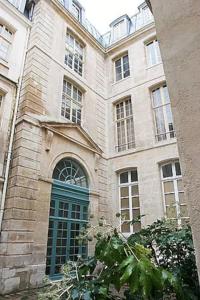 een groot stenen gebouw met een groene deur bij Charming Cosy Triplex in Trendy Marais in Parijs