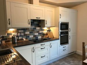 a kitchen with white cabinets and a stove top oven at Hartington House in Woodhall Spa