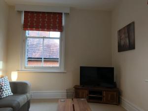 a living room with a couch and a television at Hartington House in Woodhall Spa