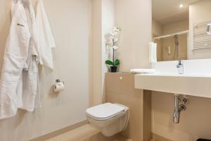 een witte badkamer met een toilet en een wastafel bij Baltic Park Molo Apartments by Zdrojowa in Świnoujście