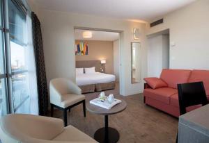 um quarto de hotel com uma cama e um sofá em Best Western Hotel Sourcéo em Saint-Paul-lès-Dax