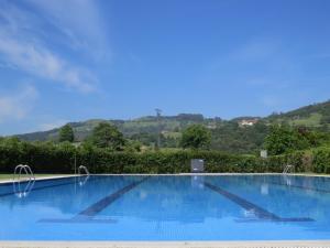 una gran piscina azul con una colina de fondo en Hotel Rural El Solar del Mazo en Rada