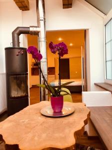 een tafel met een vaas met paarse bloemen erop bij Echt Heimat Apartments in Sankt Gilgen