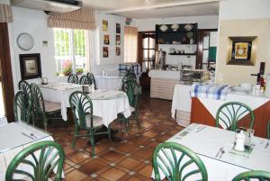 un restaurante con mesas blancas y sillas verdes en Hotel Hermes, en Tossa de Mar