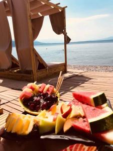 a plate of fruit on a table near the water at Nana Hotel in Kamena Vourla
