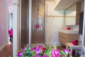 y baño con ducha con flores púrpuras. en Chez Constance en Saillon