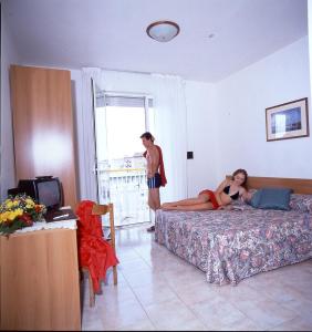 a woman laying on a bed in a bedroom with a man at Maxi Heron in Lido di Jesolo