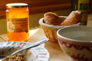 a table with a basket of bread and a bowl of honey at Auberge de la Perdrix in Hauterive-la-Fresse