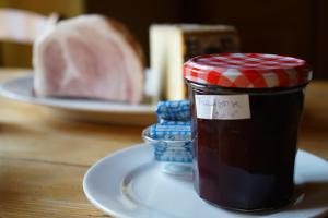 a jar of jam on a plate with a piece of meat at Auberge de la Perdrix in Hauterive-la-Fresse