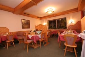 ein Restaurant mit Tischen und Stühlen mit rotem Tischtuch in der Unterkunft Hotel Alpenrose in Tauplitzalm
