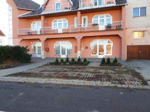 una casa rosa con un patio frente a ella en Kertvárosi Apartman II, en Tiszaújváros