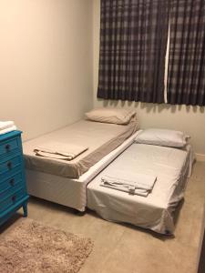 2 camas en un dormitorio con vestidor azul y ventana en Apto 2suítes 30m da praia, en Florianópolis