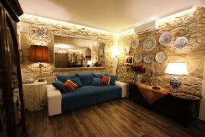 a living room with a blue couch and a stone wall at Kimera in Piazza Armerina