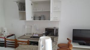 a kitchen with white cabinets and a table with a microwave at Condomínio Mont Hebron - Apto 3A in Porto Seguro +1 photo