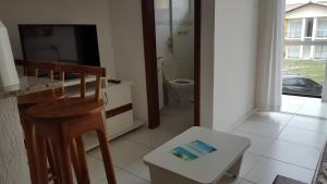 a bathroom with a toilet and a television and a stool at Condomínio Mont Hebron - Apto 3A in Porto Seguro