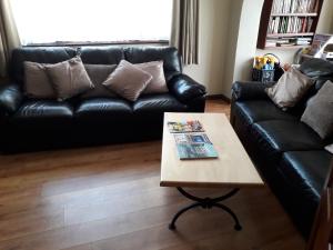 a living room with a black leather couch and a coffee table at Melrose B&B in Clonakilty