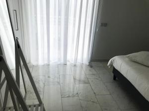 a bedroom with white curtains and a bed and a tiled floor at Olosuites in Limassol