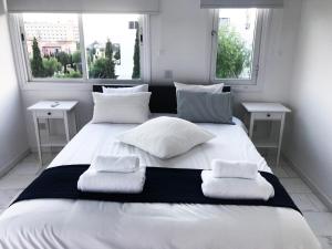 a large white bed with two pillows and two windows at Olosuites in Limassol
