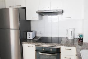 a kitchen with a stainless steel refrigerator and white cabinets at Olosuites in Limassol